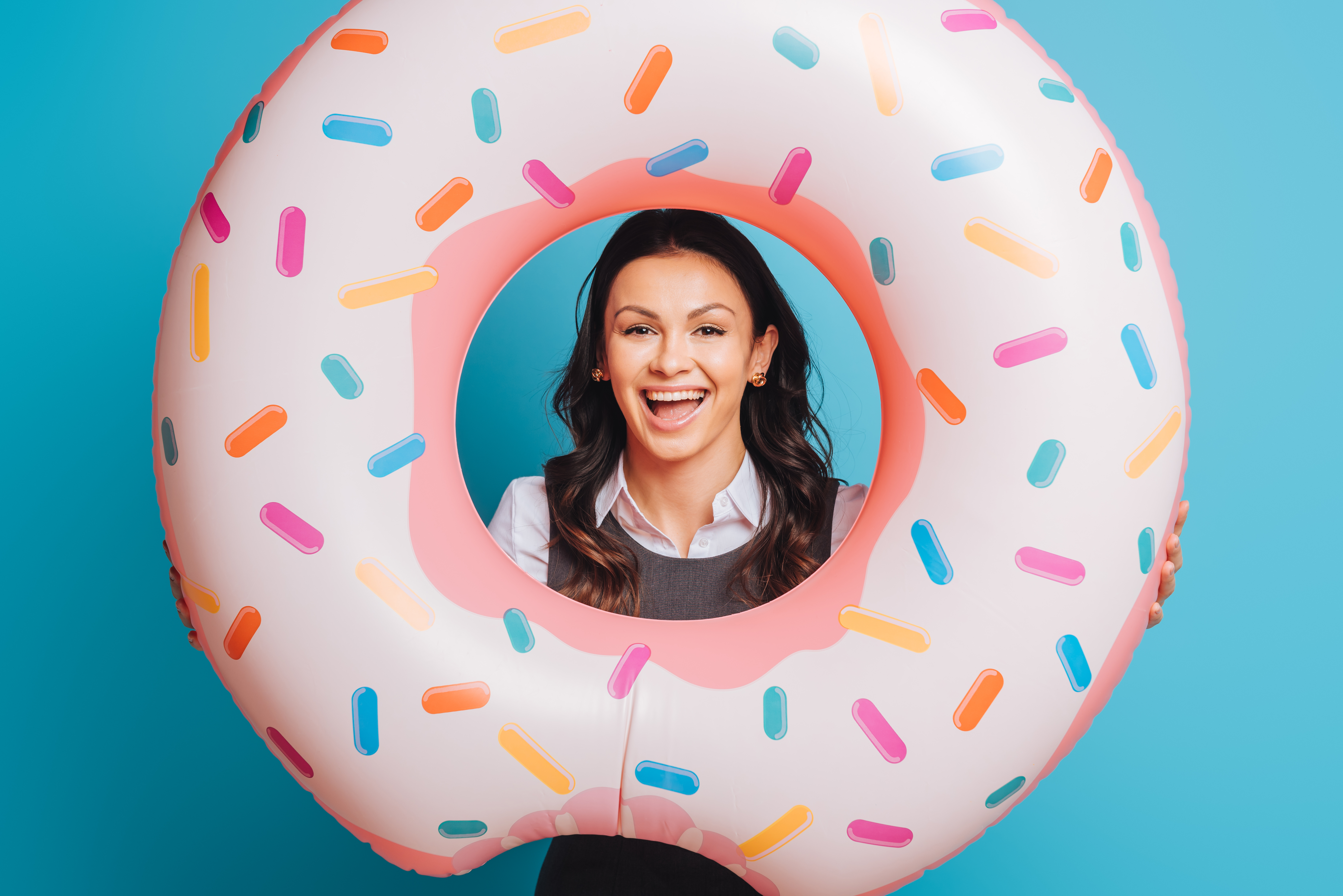 cheerful businesswoman with swim ring smiling at camera on blue background